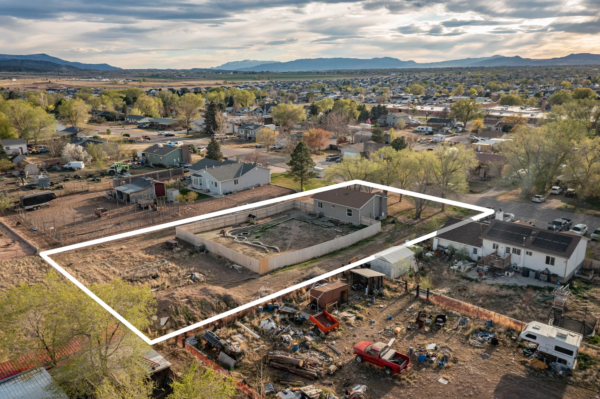 Aerial view of property's location with property boundaries highlighted, a mountainous background, and nearby suburban area