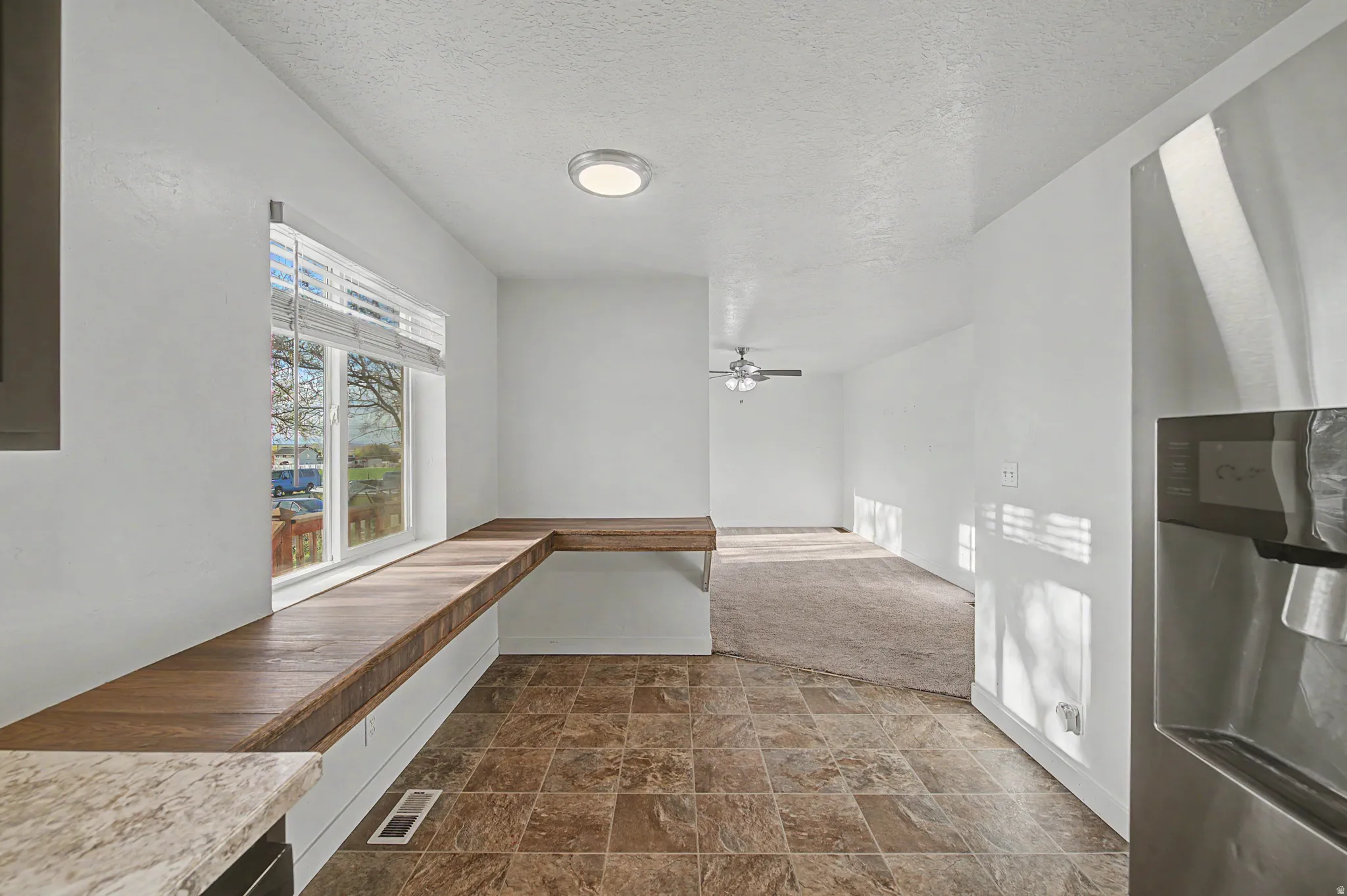 Corridor featuring stone finish floors, a textured ceiling, and dark carpet