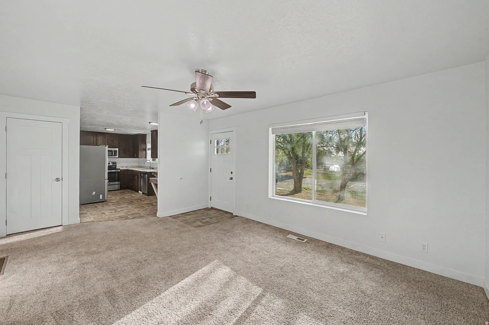 Unfurnished living room featuring ceiling fan and light carpet