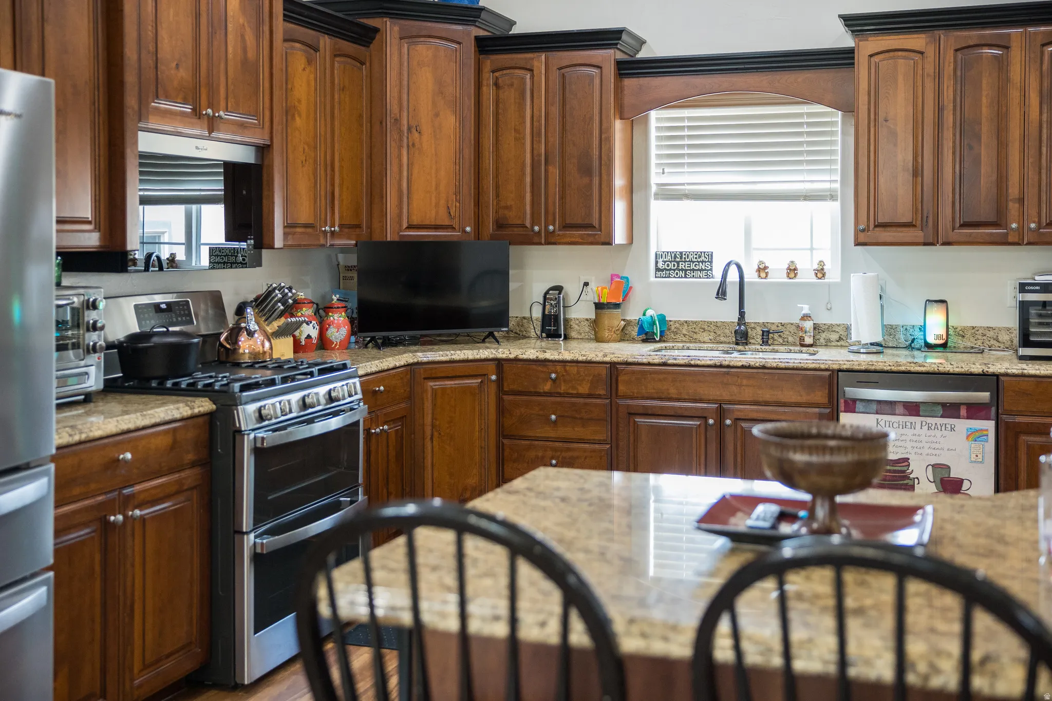 Kitchen featuring stainless steel appliances, light stone counters, and wood finish cabinetry