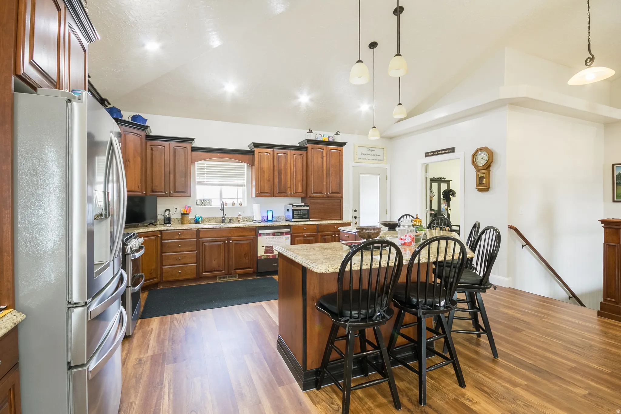 Kitchen with stainless steel appliances, lofted ceiling, a kitchen island, dark wood-type flooring, and a breakfast bar