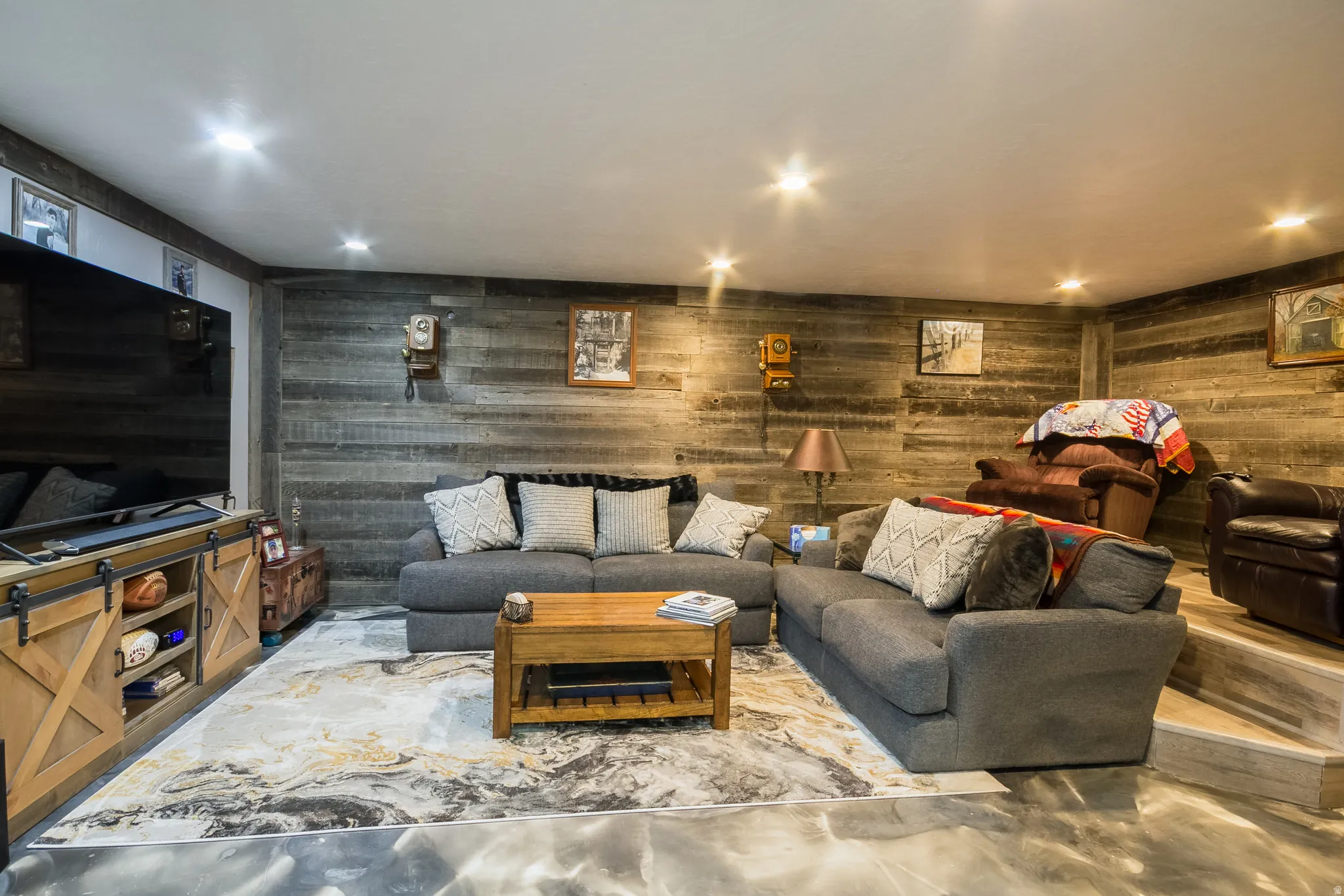 Living room featuring concrete flooring, recessed lighting, and wood walls