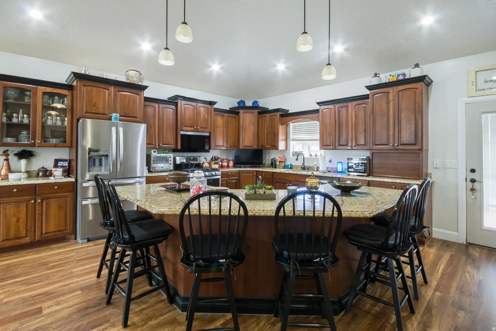Kitchen with stainless steel appliances, a kitchen bar, and light stone counters