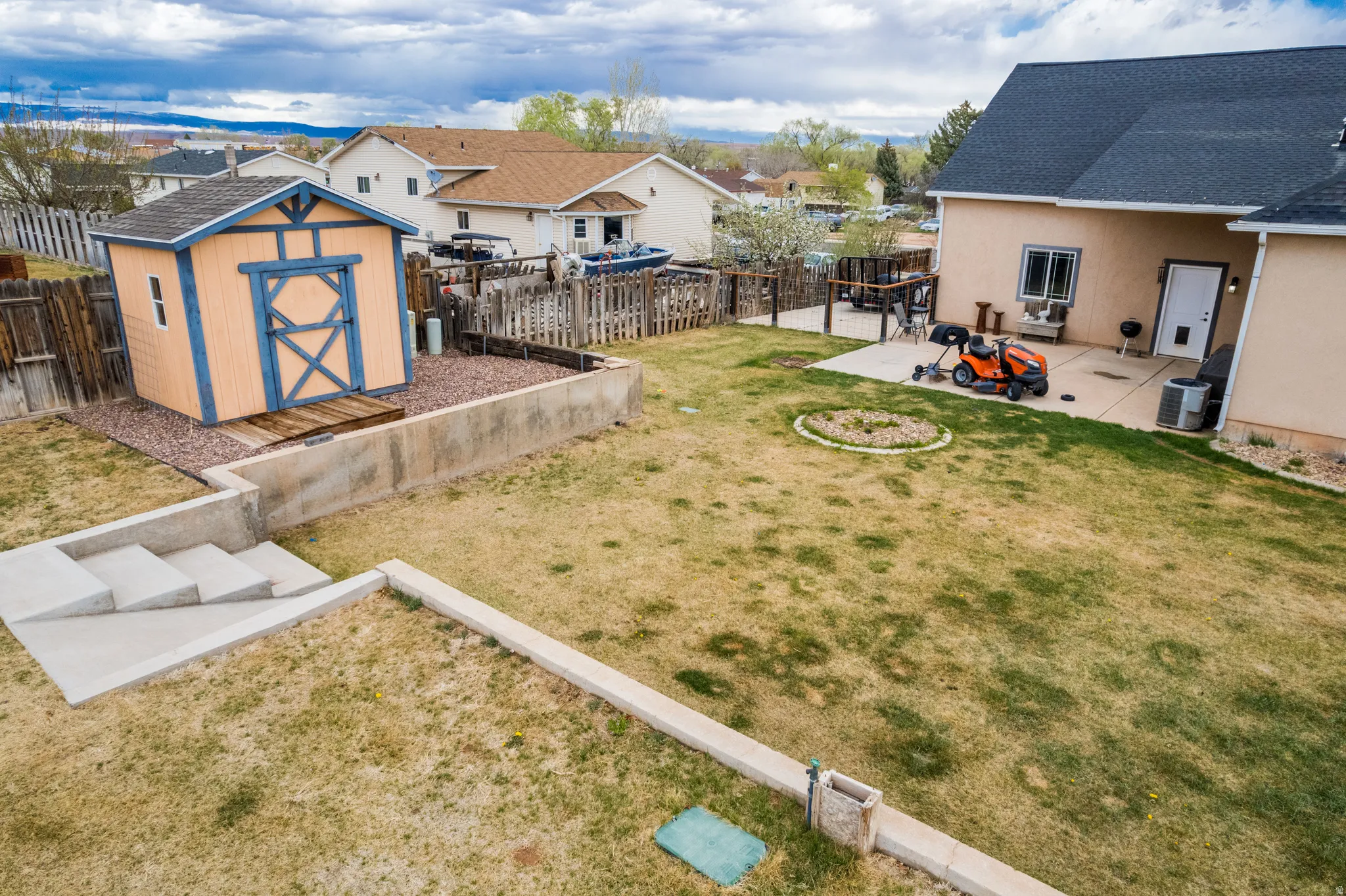 Fenced backyard featuring a patio area, a storage shed, and a residential view