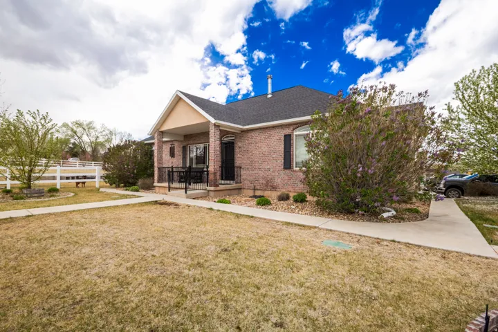 Ranch-style house featuring brick siding, a front lawn, a porch, and roof with shingles