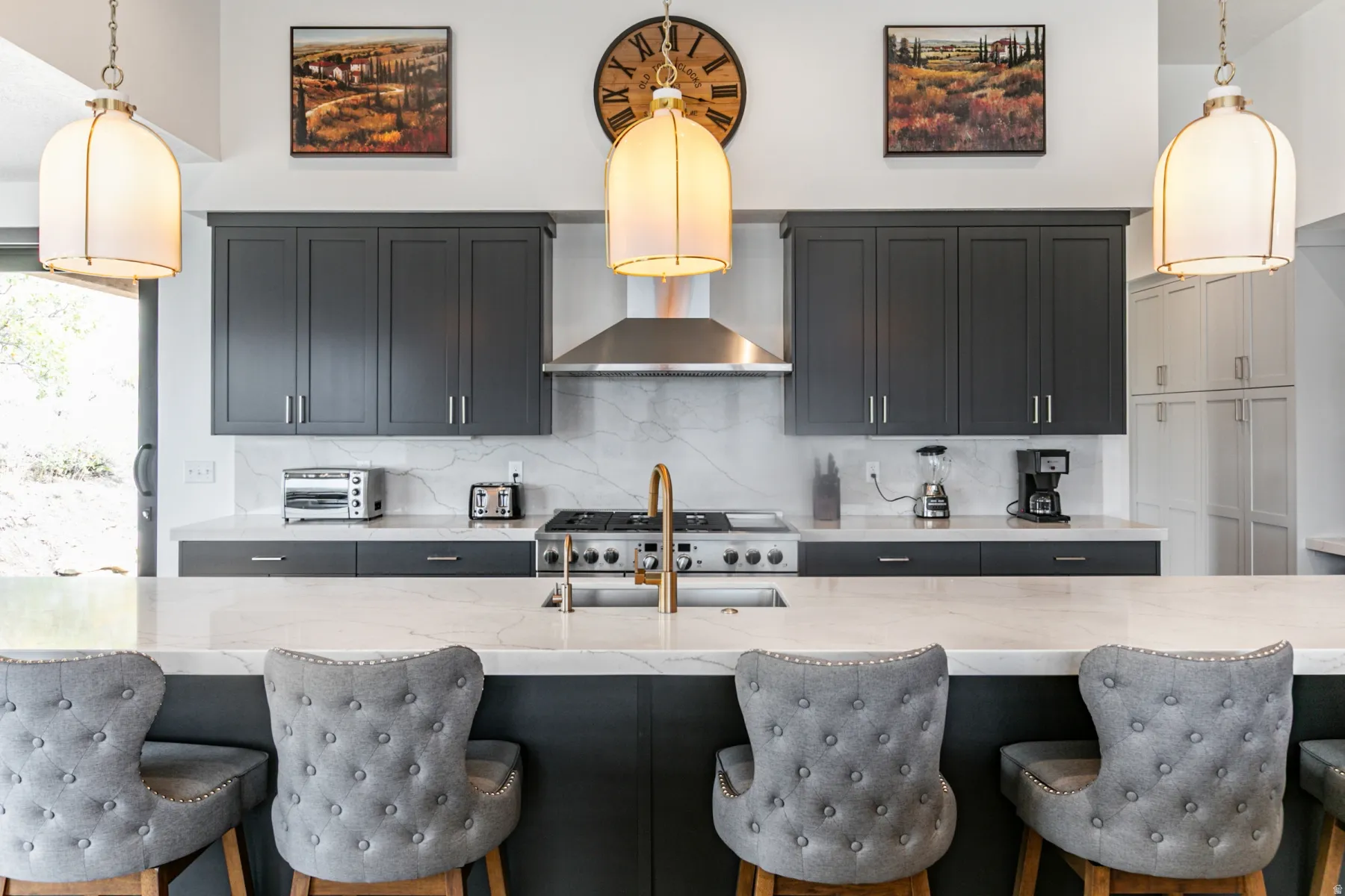 Kitchen featuring decorative light fixtures, light stone counters, tasteful backsplash, and dark cabinetry