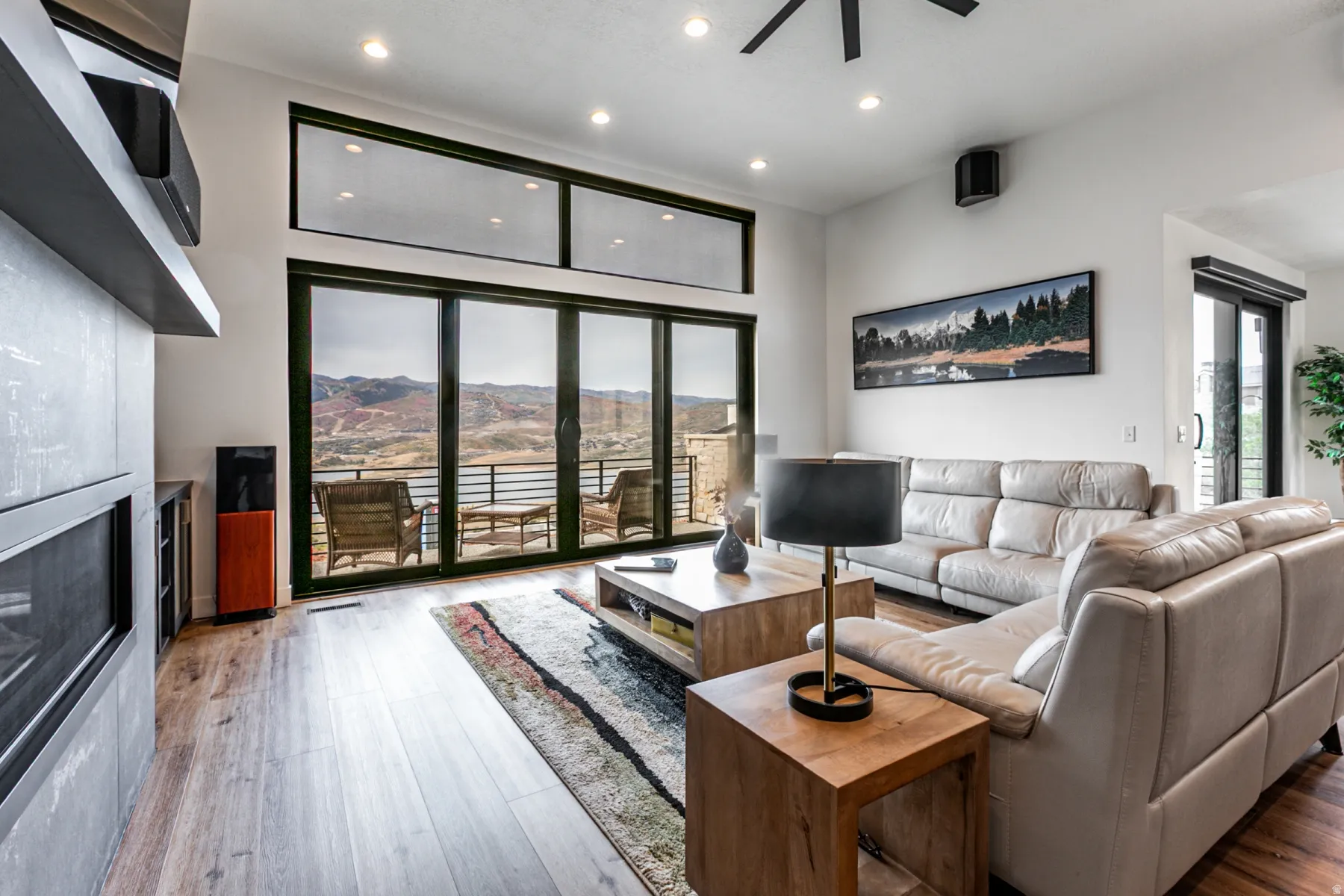 Living room featuring light wood-type flooring, recessed lighting, a ceiling fan, and a glass covered fireplace