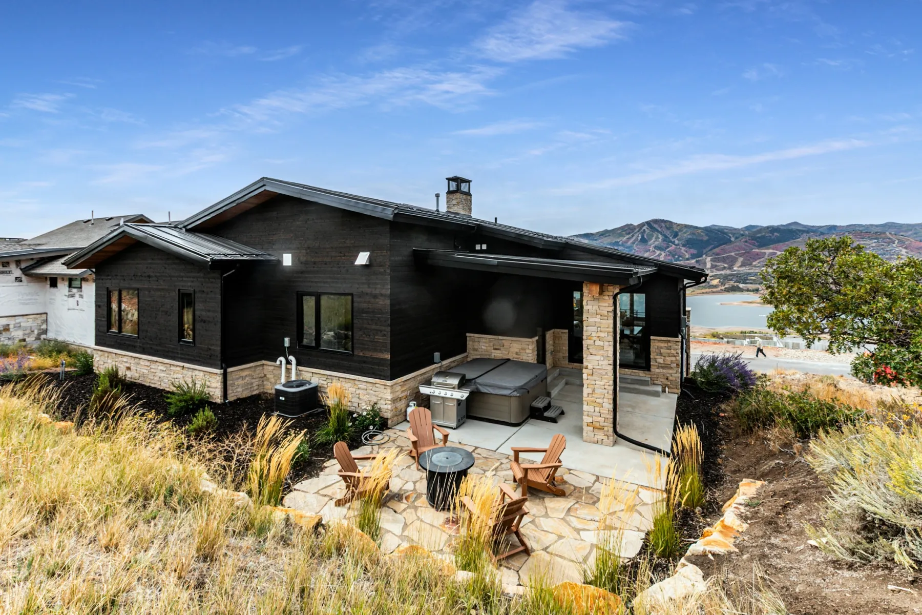 Rear view of house with stone siding, a patio, a chimney, an outdoor fire pit, and a mountain view