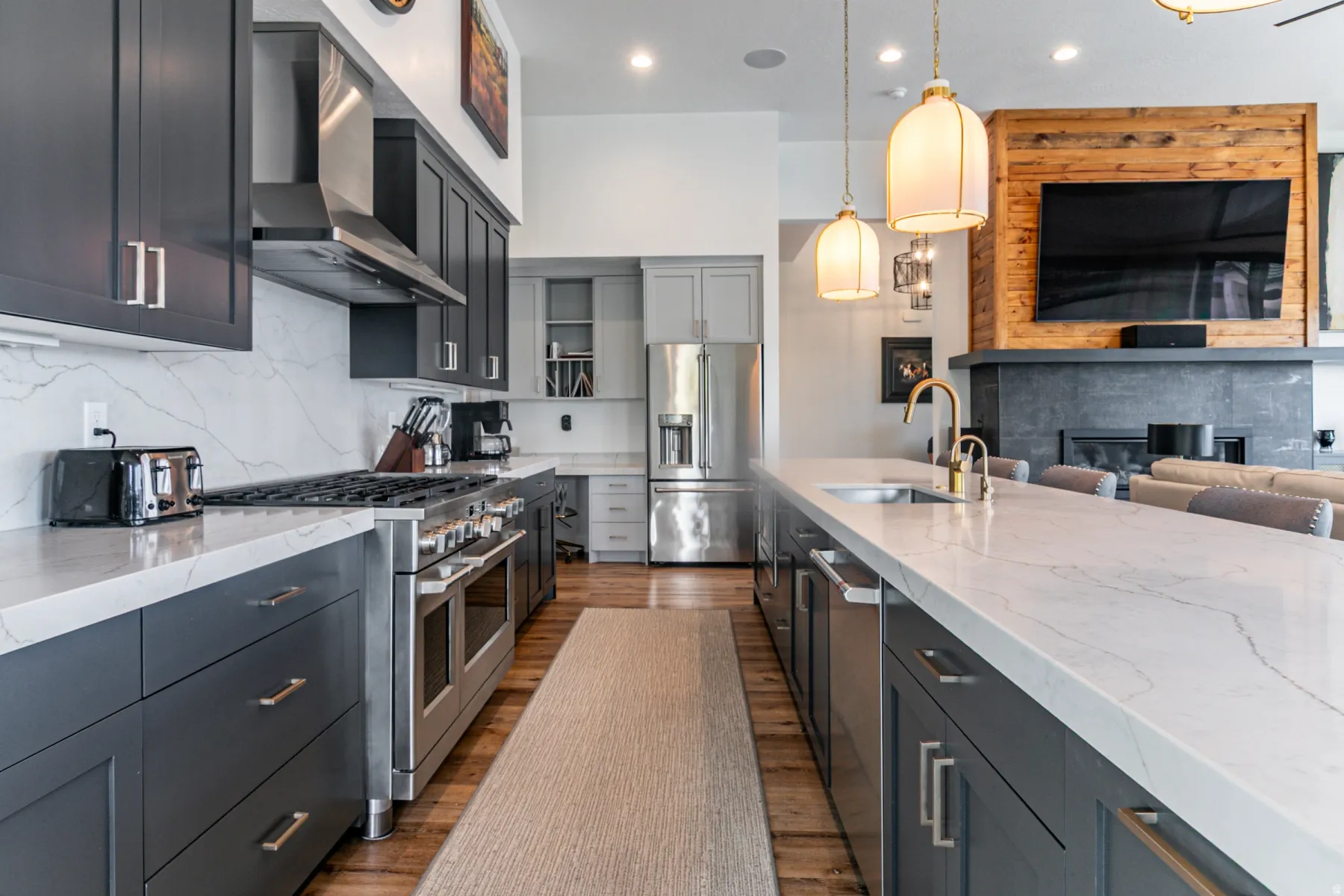 Kitchen featuring premium appliances, light stone counters, backsplash, open floor plan, and pendant lighting