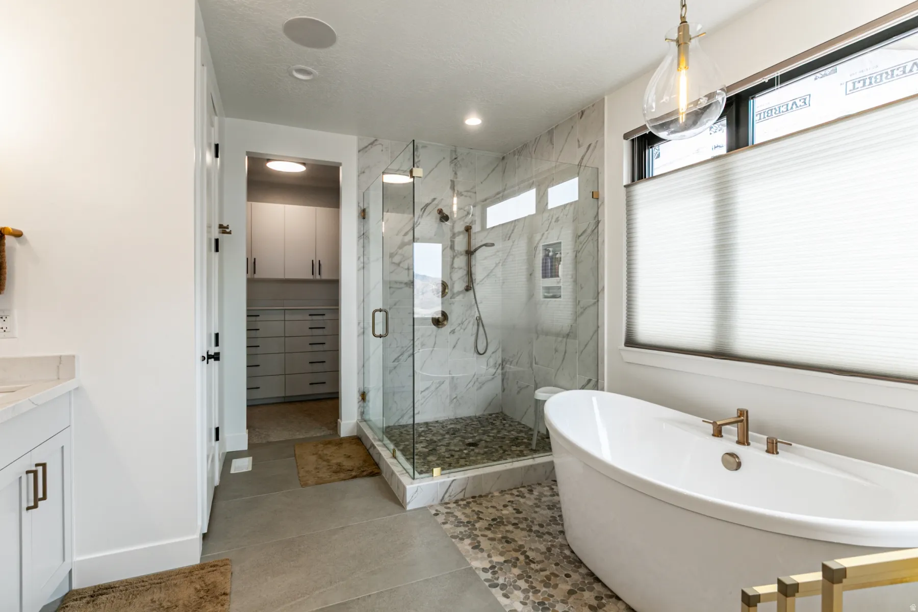 Bathroom with a marble finish shower, a soaking tub, vanity, a walk in closet, and recessed lighting