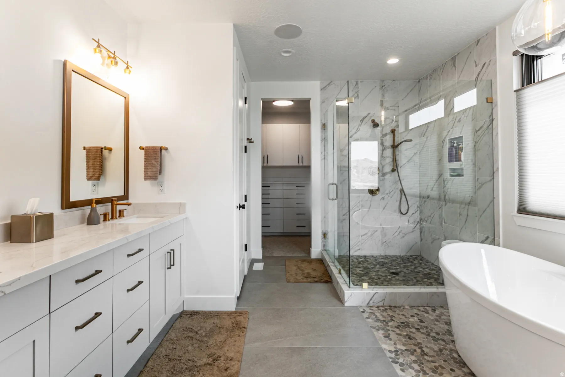 Bathroom with a marble finish shower, a soaking tub, vanity, a spacious closet, and recessed lighting