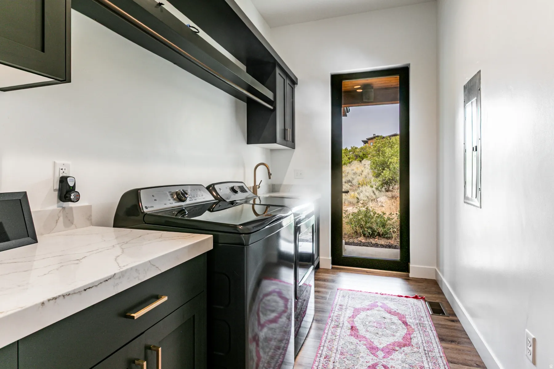 Laundry room with dark wood-type flooring, cabinet space, and washer and clothes dryer