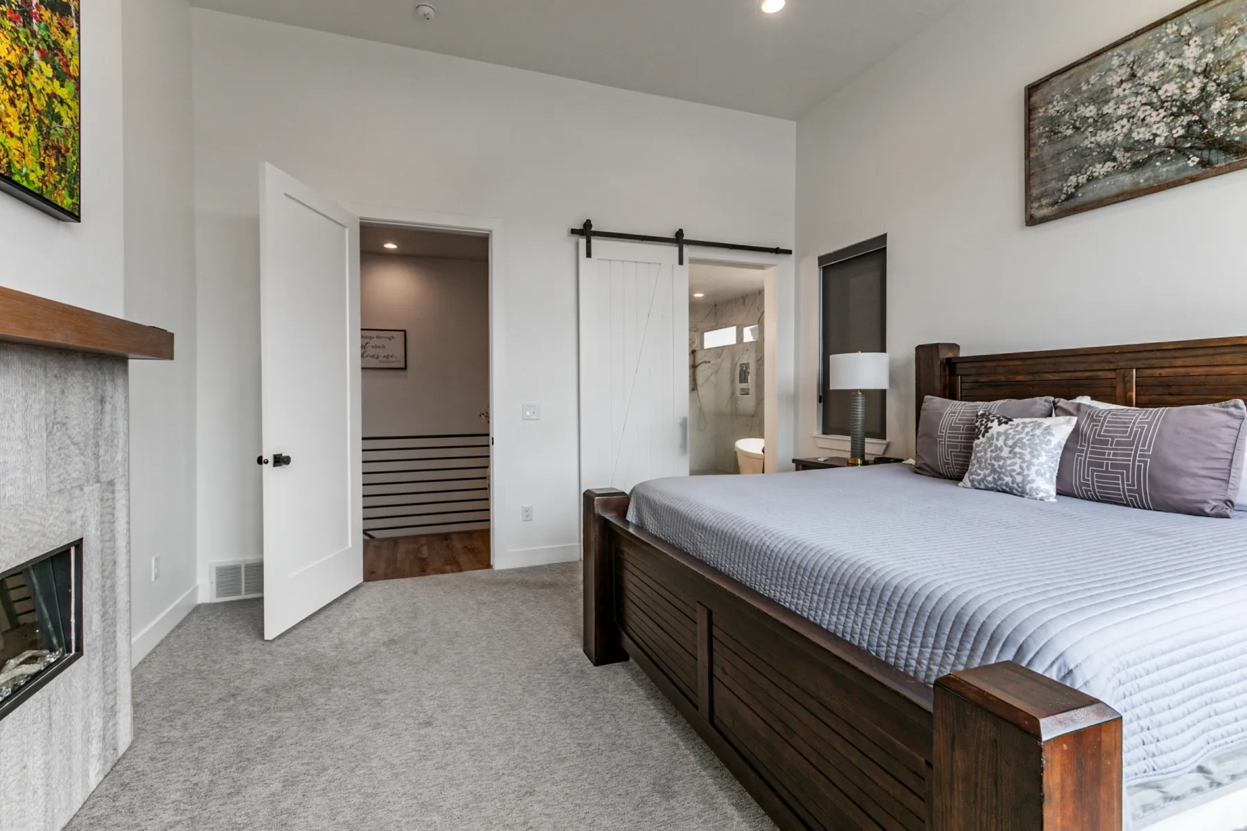 Bedroom featuring light colored carpet, a barn door, ensuite bath, a fireplace, and recessed lighting