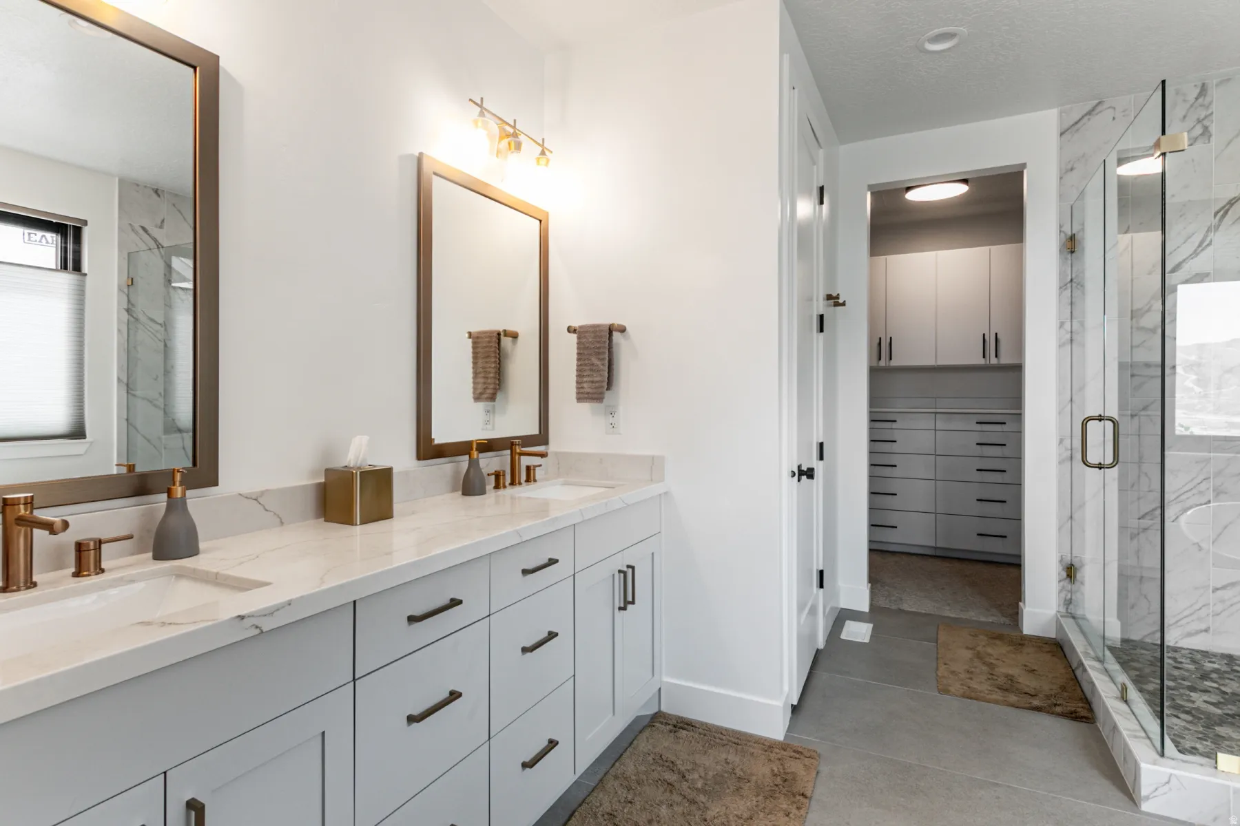 Bathroom featuring a marble finish shower, double vanity, a spacious closet, and a textured ceiling