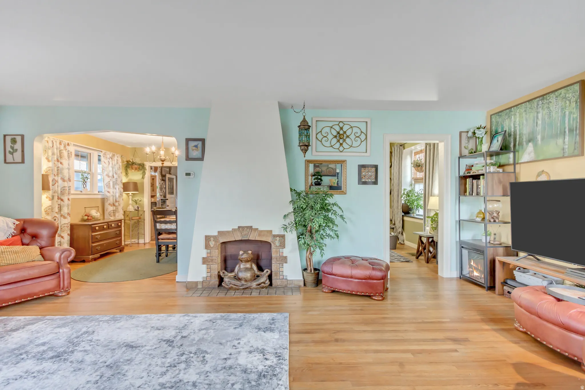Living room featuring light wood-type flooring, hanging lights, arched walkways, and a fireplace with flush hearth
