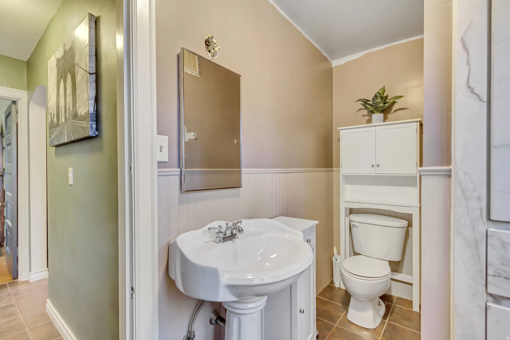 Half bathroom featuring a wainscoted wall, ornamental molding, and light tile patterned flooring