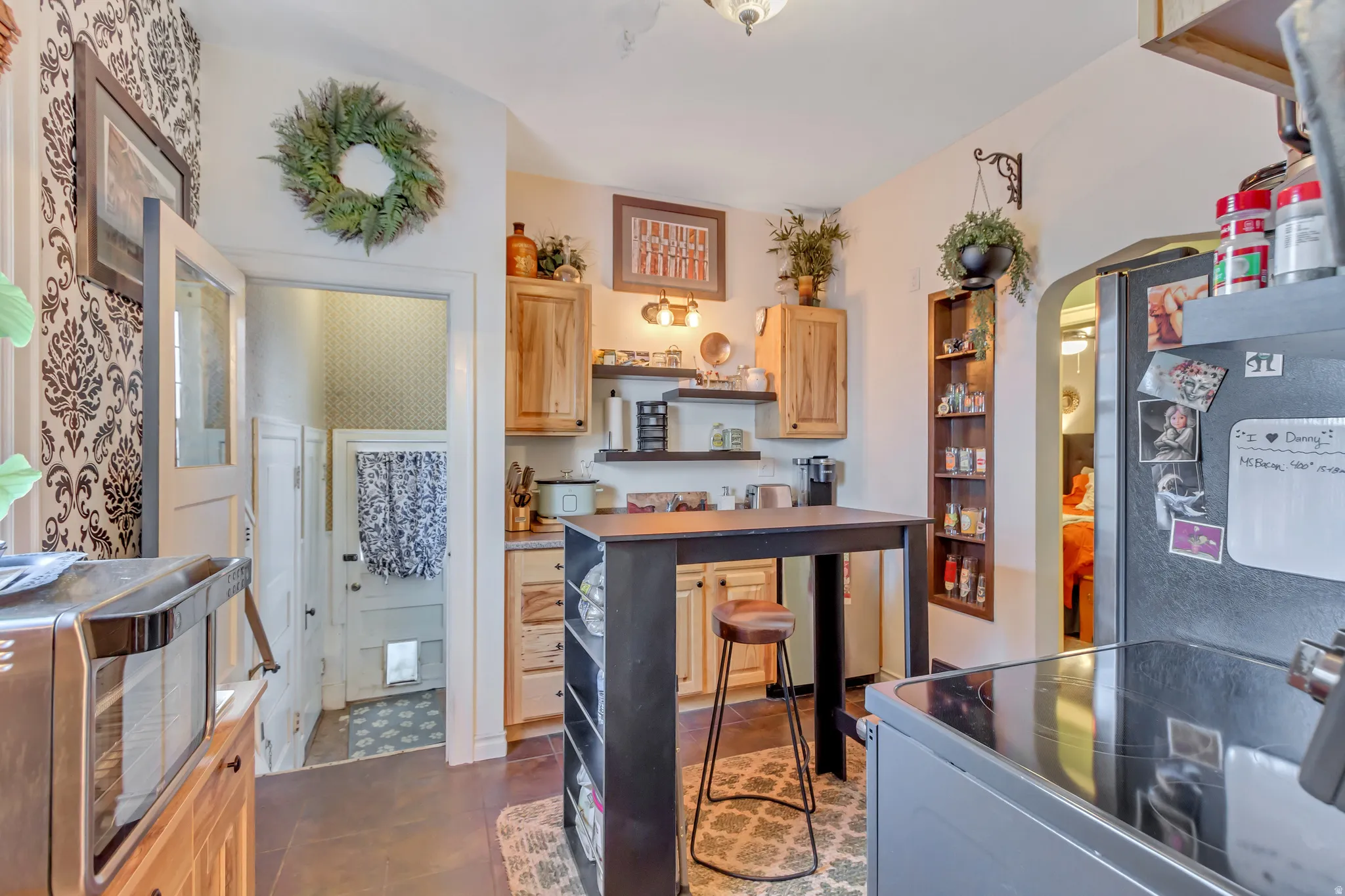 Kitchen featuring light wood finish cabinets, range with electric stovetop, arched walkways, open shelves, and freestanding refrigerator