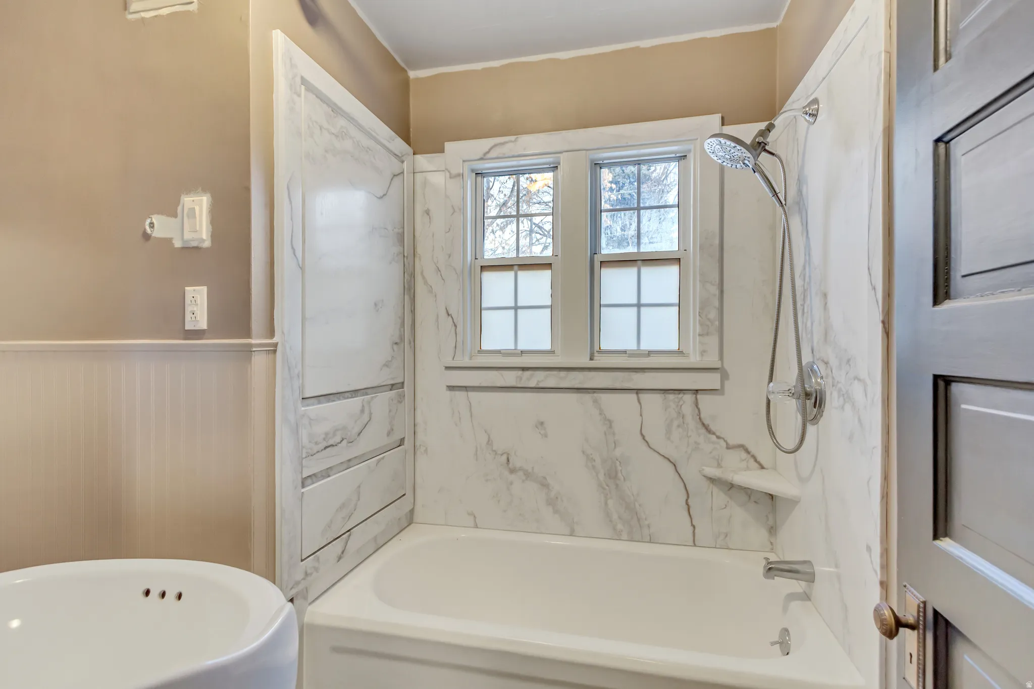 Full bathroom featuring a combined bath / shower with marble appearance, a wainscoted wall, and ornamental molding
