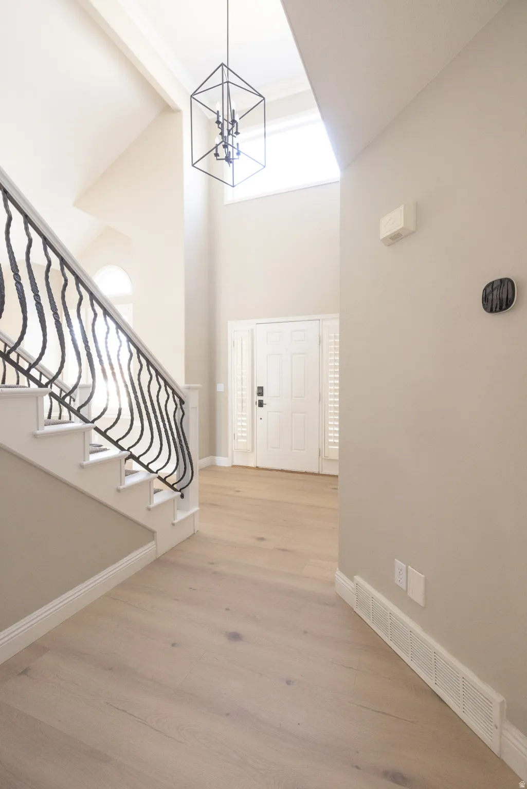 Foyer entrance featuring light wood-style floors, suspended lighting, and lofted ceiling