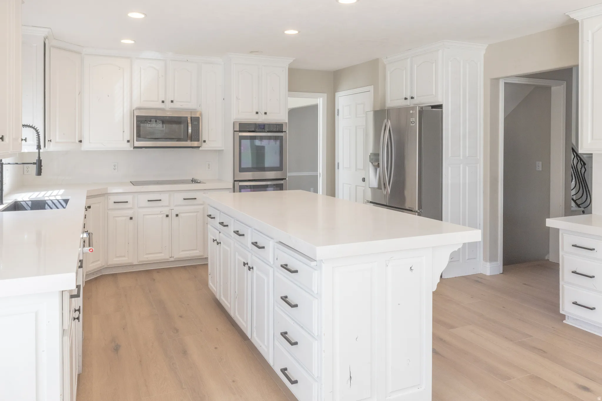 Kitchen with white cabinetry, stainless steel appliances, recessed lighting, and a center island