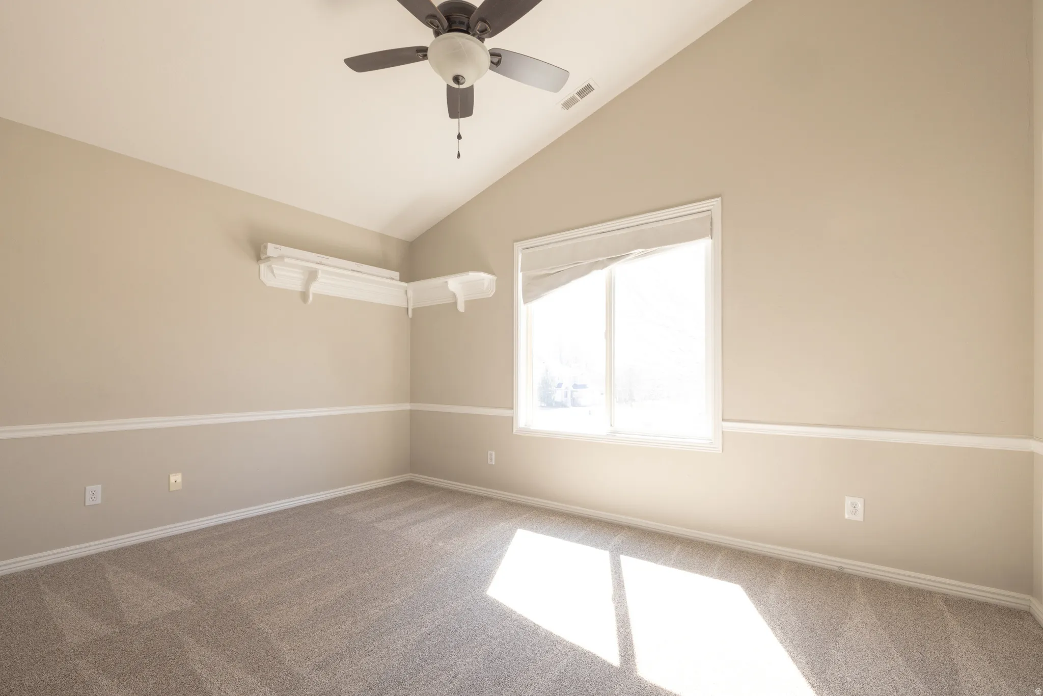 Carpeted spare room with vaulted ceiling and a ceiling fan