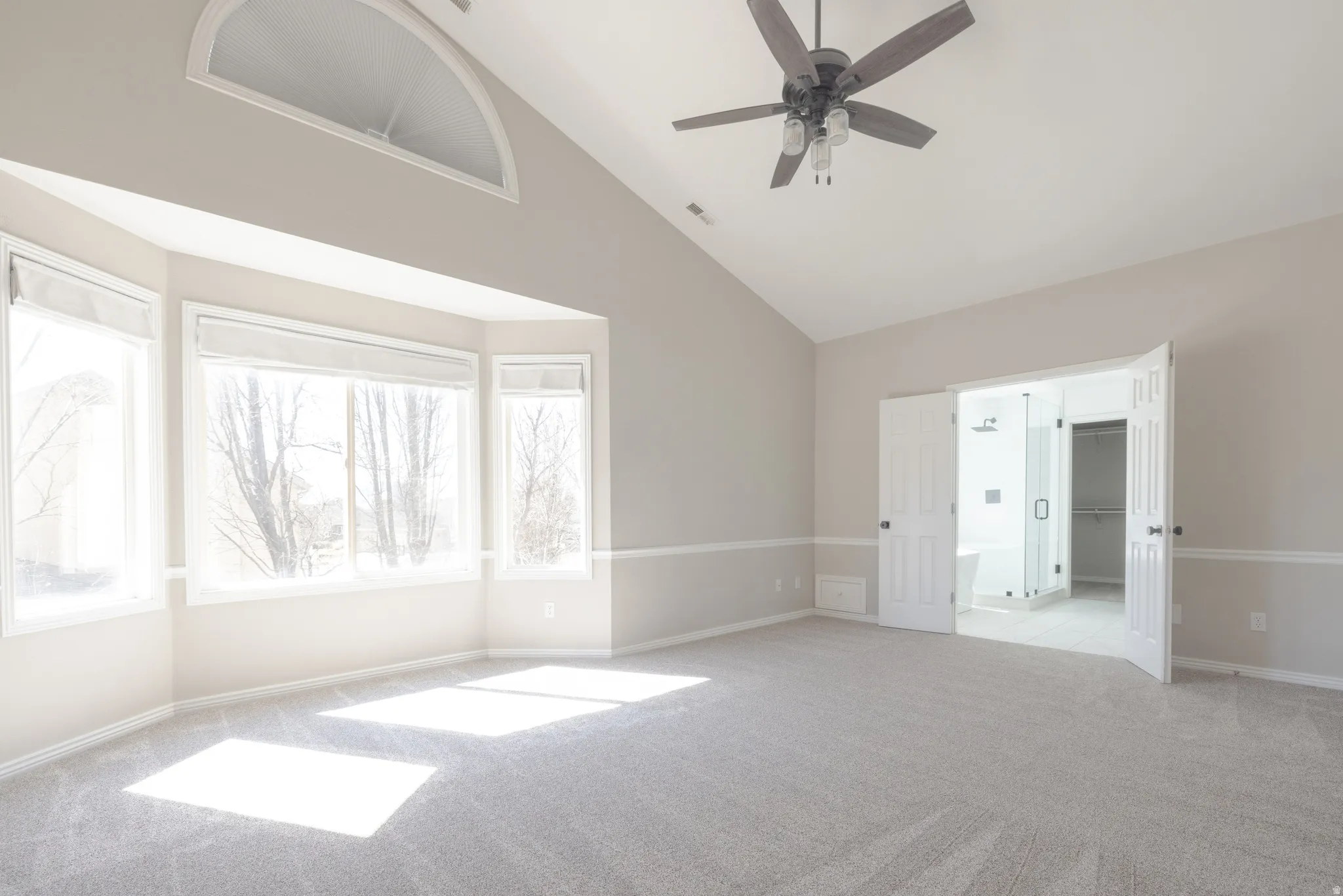Unfurnished room with light colored carpet, a ceiling fan, and lofted ceiling