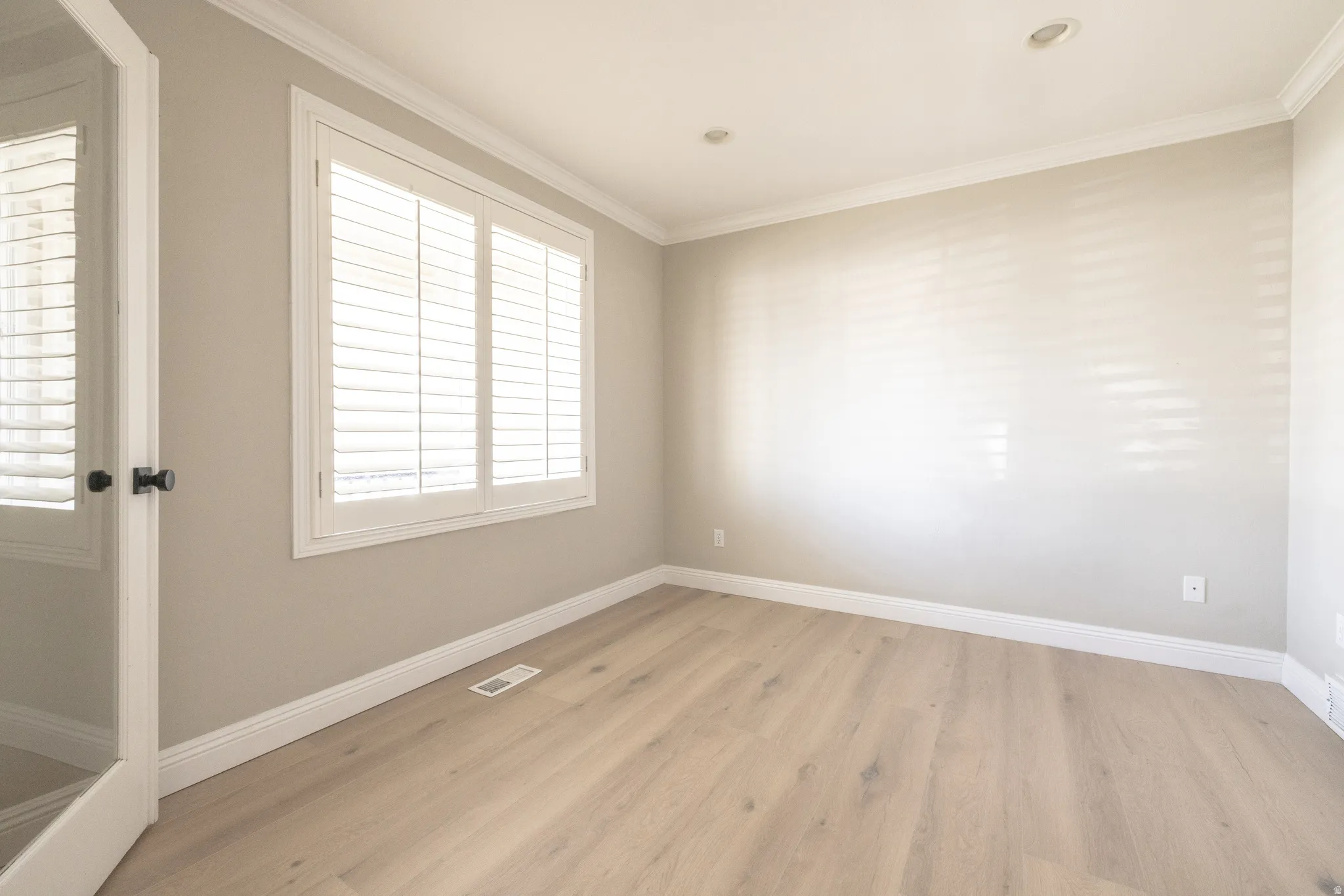 Empty room with light wood-type flooring and crown molding