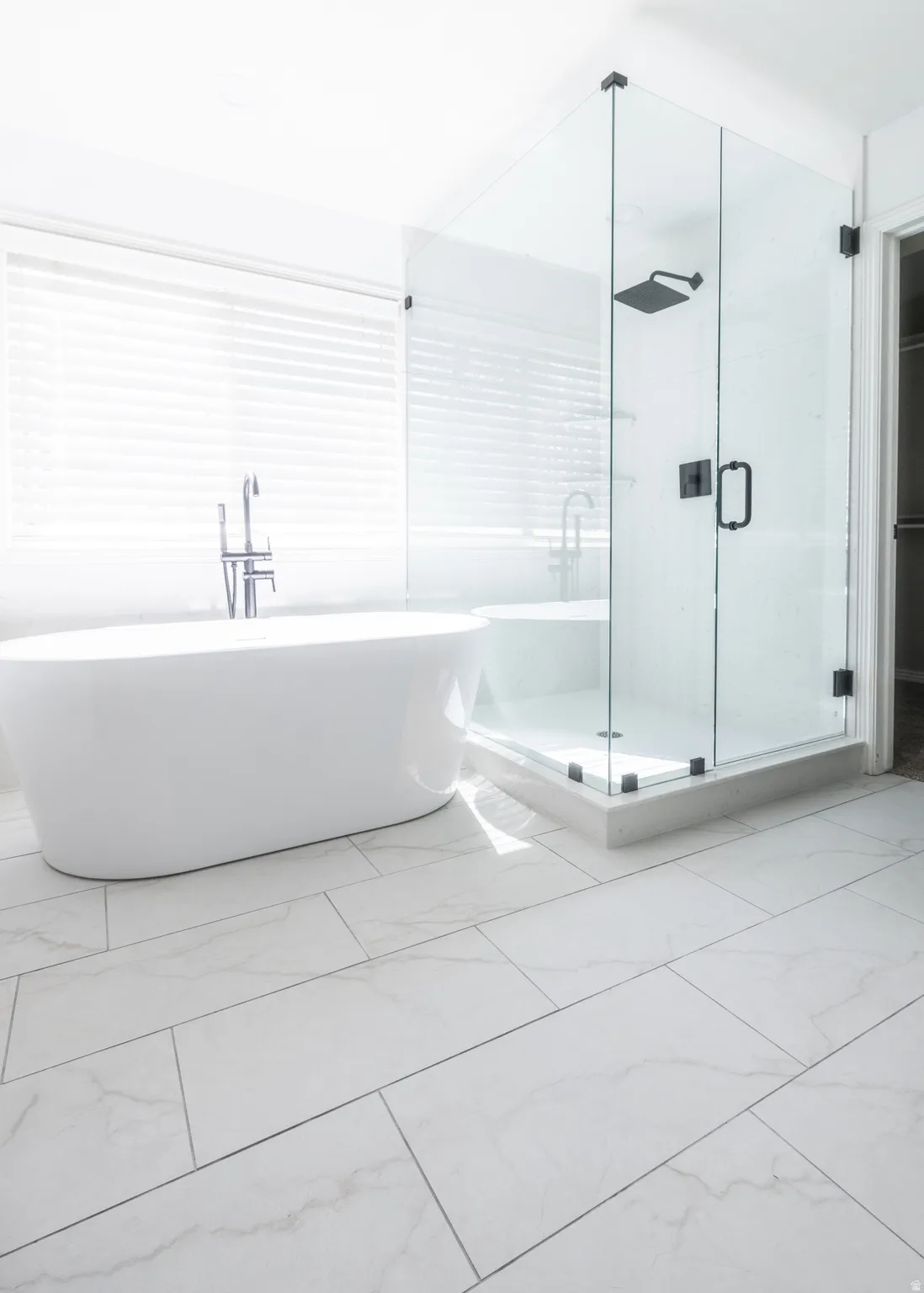 Bathroom featuring light marble finish floors, a shower stall, and a freestanding bath