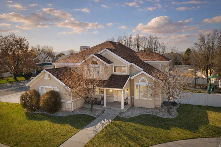 View of front facade with a front lawn, a porch, a chimney, and stucco siding
