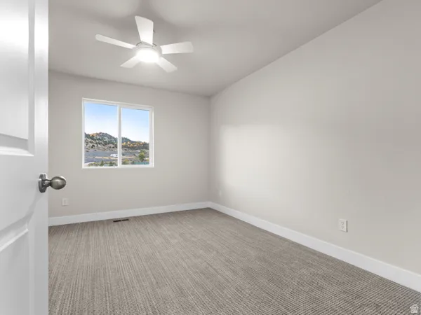 Empty room with light carpet and a ceiling fan