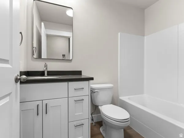 Bathroom featuring vanity, dark wood finished floors, and washtub / shower combination