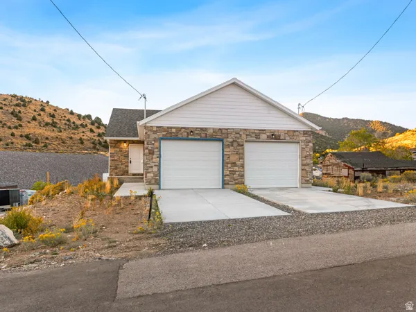 Single story home featuring a mountain view, concrete driveway, and stone siding