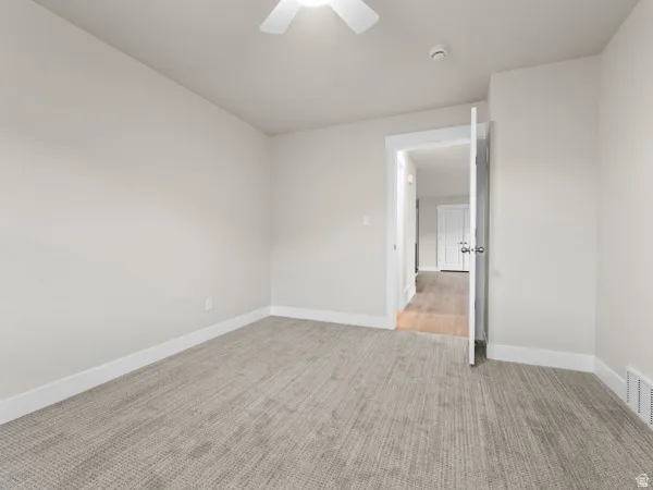 Spare room with light colored carpet and a ceiling fan