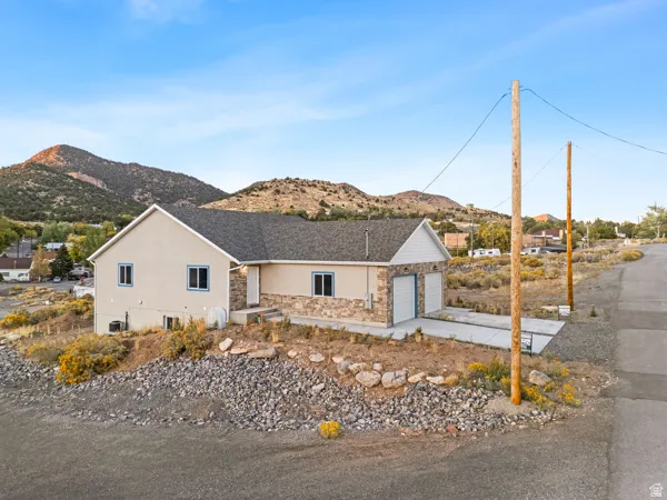 Ranch-style home featuring stone siding, stucco siding, a mountain view, a garage, and driveway