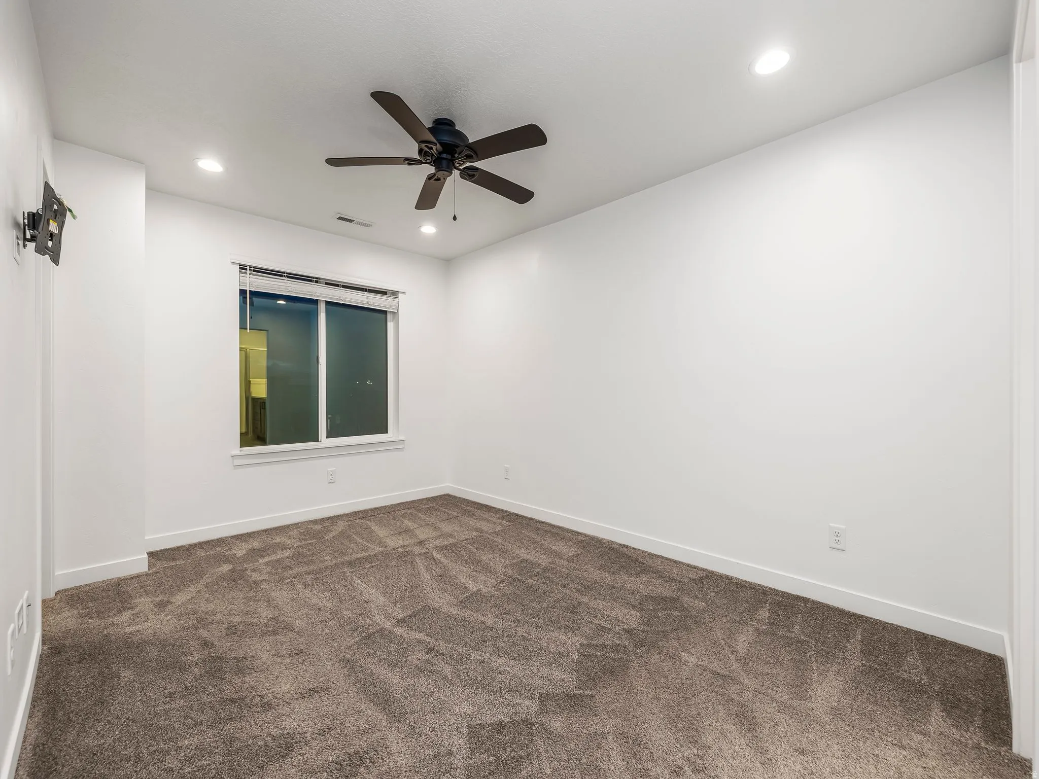 Spare room featuring dark colored carpet, ceiling fan, and recessed lighting