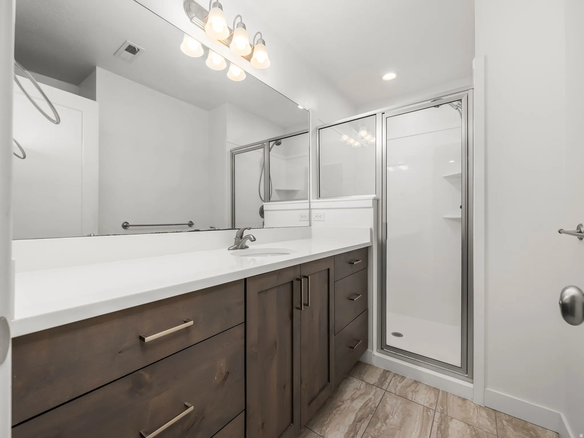Bathroom with a stall shower, vanity, and recessed lighting
