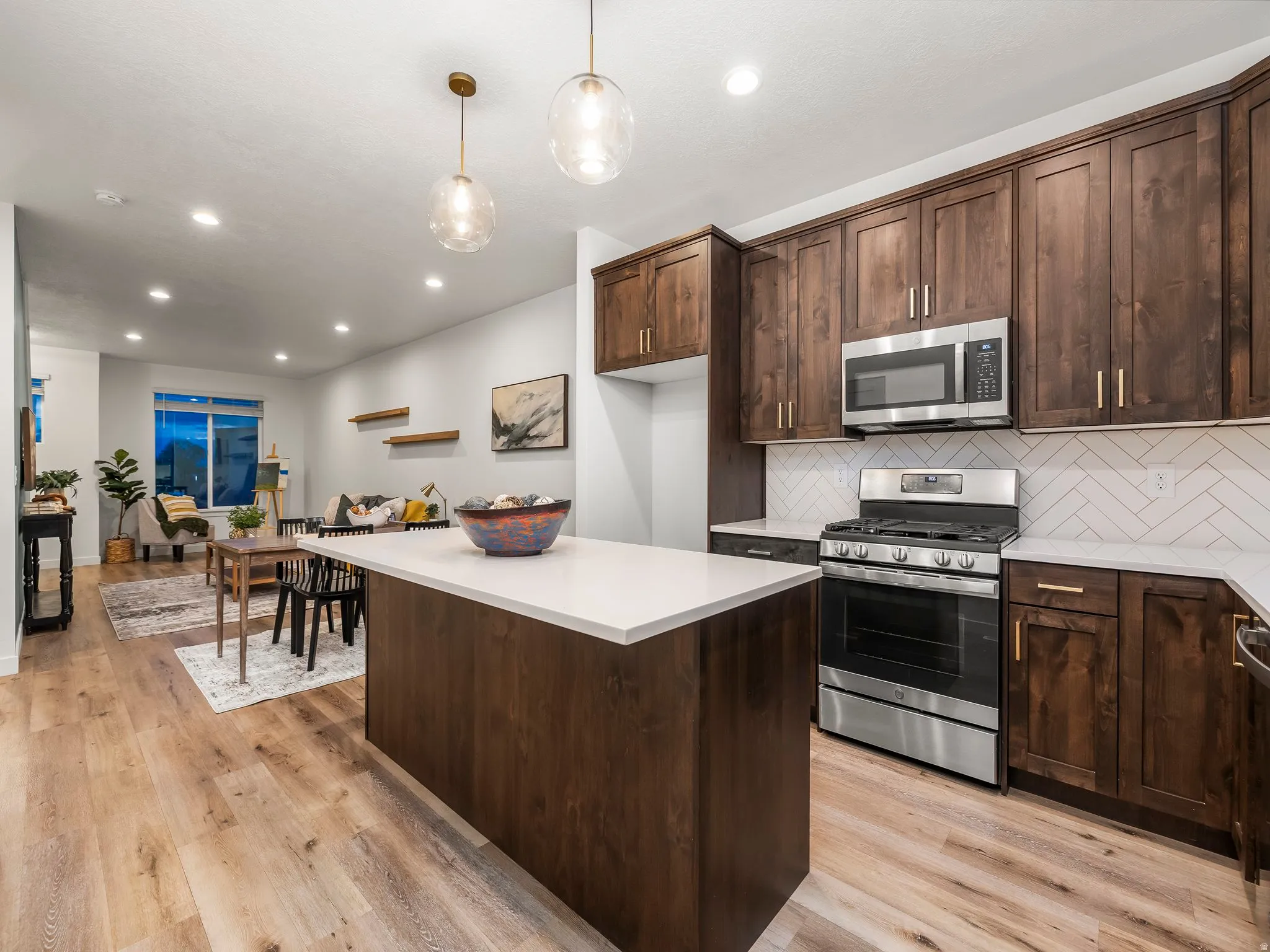 Kitchen featuring dark wood finish cabinets, stainless steel appliances, backsplash, a center island, and light wood finished floors