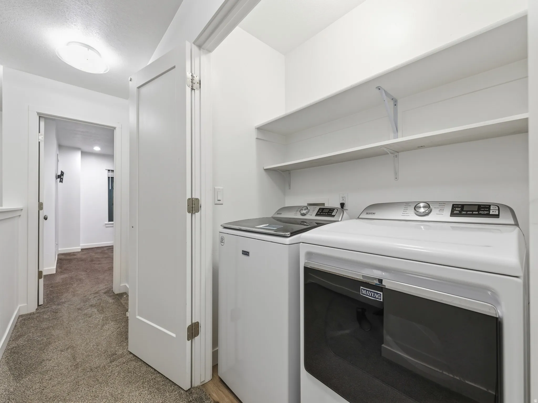 Laundry area with light carpet and washing machine and dryer