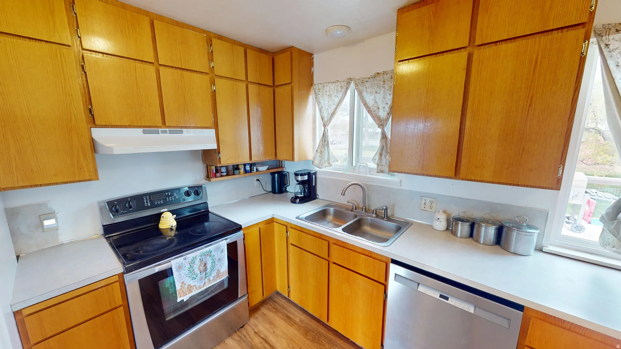 Kitchen with stainless steel appliances, light countertops, wood finish cabinetry, and light wood-type flooring