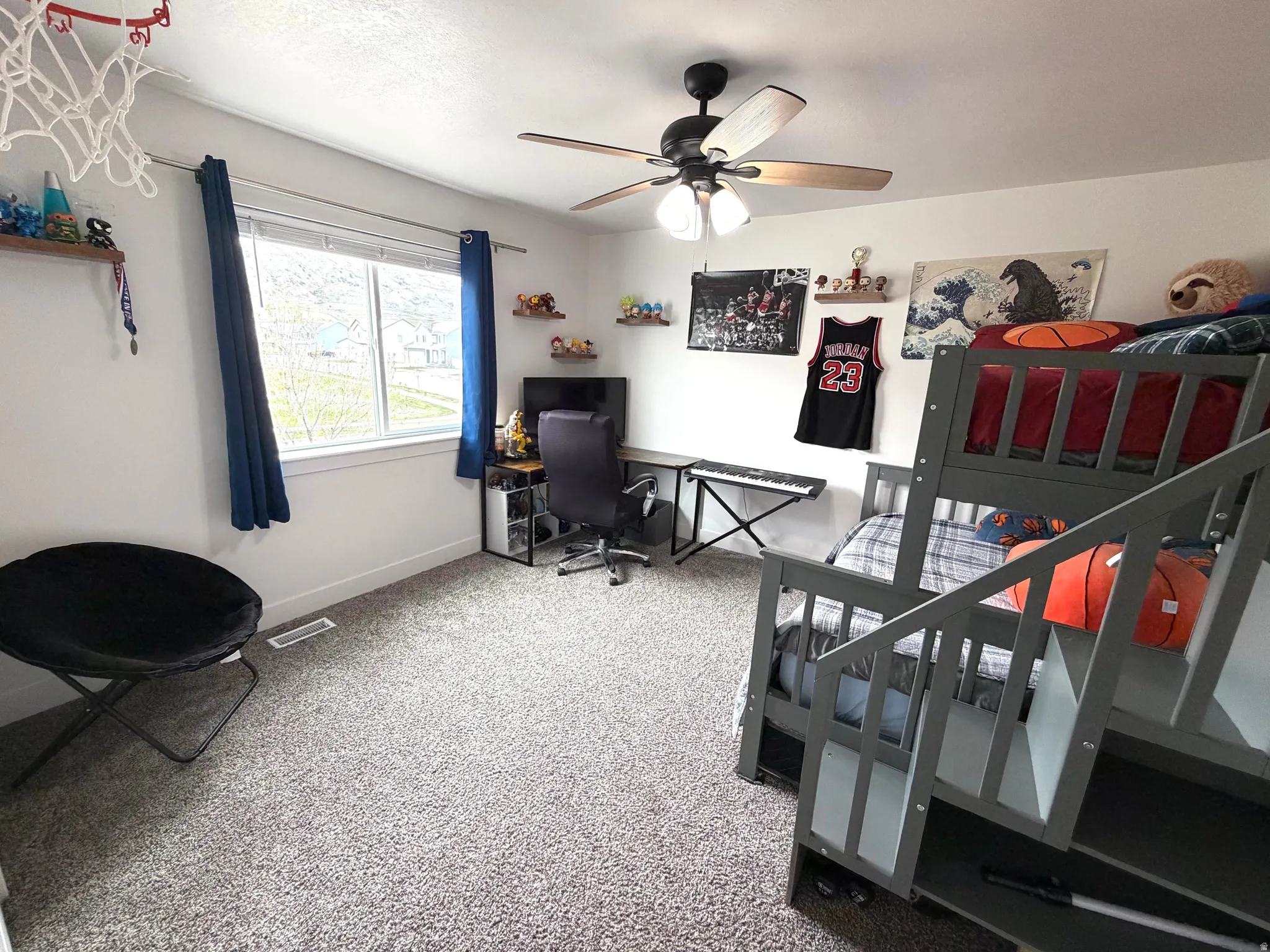 Bedroom with light carpet, a ceiling fan, and a desk