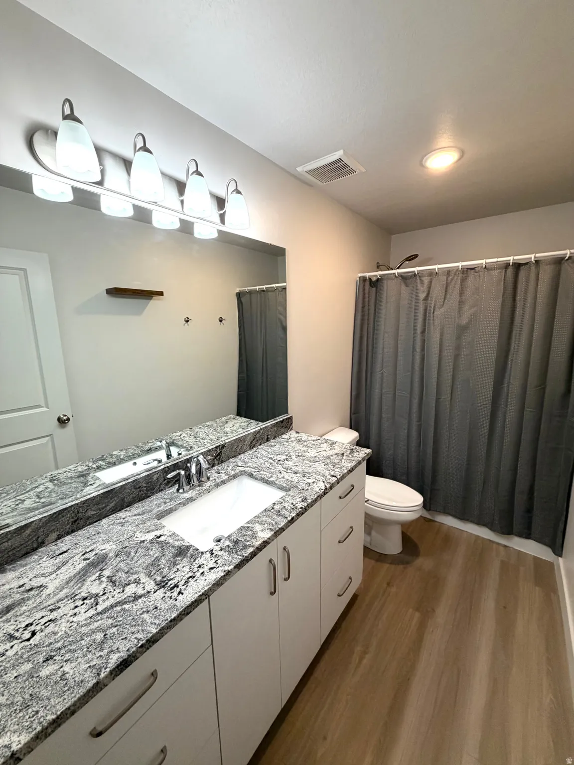 Bathroom with vanity, a shower with shower curtain, and dark wood finished floors