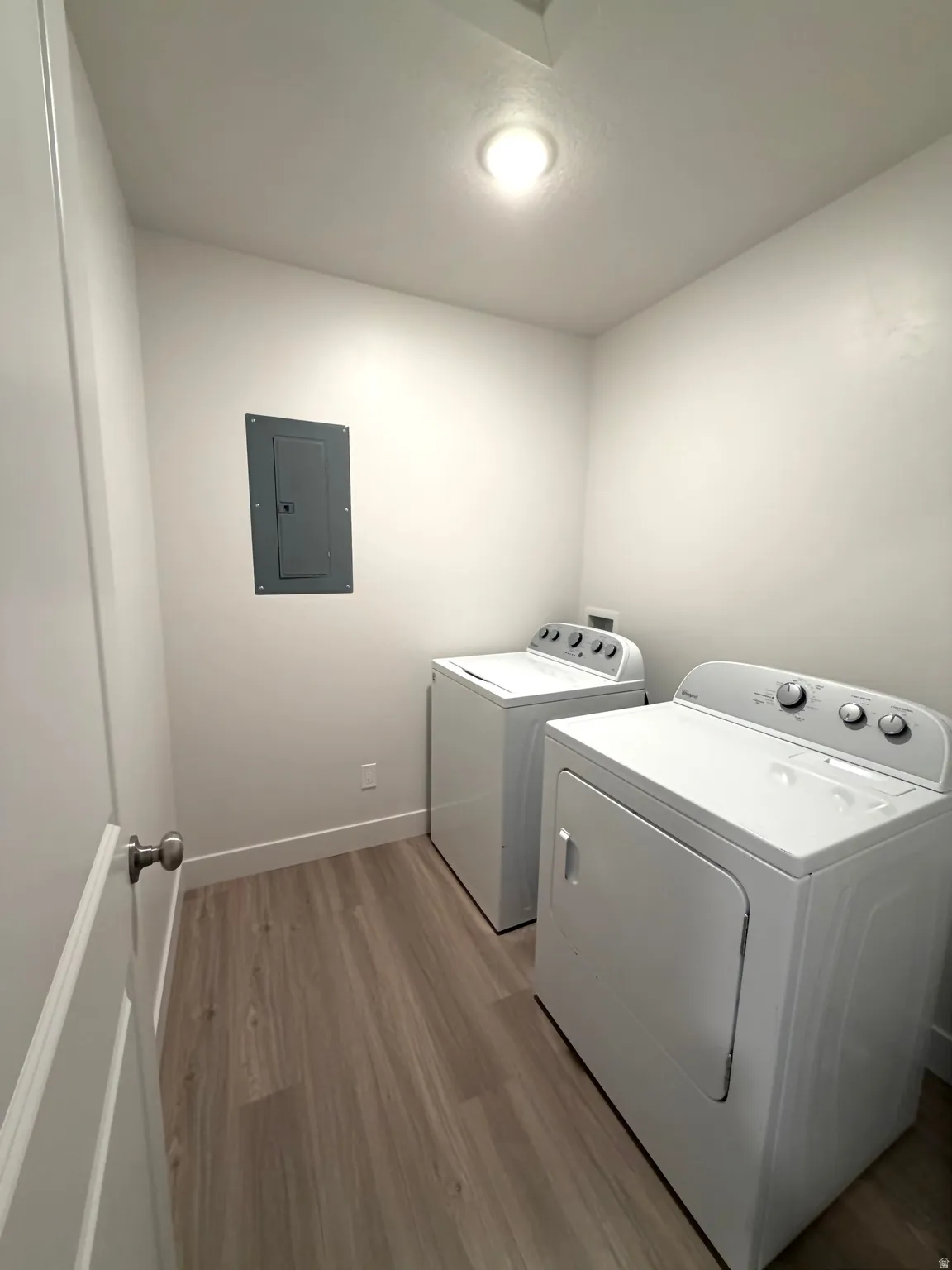 Laundry room featuring light wood finished floors, electric panel, and separate washer and dryer
