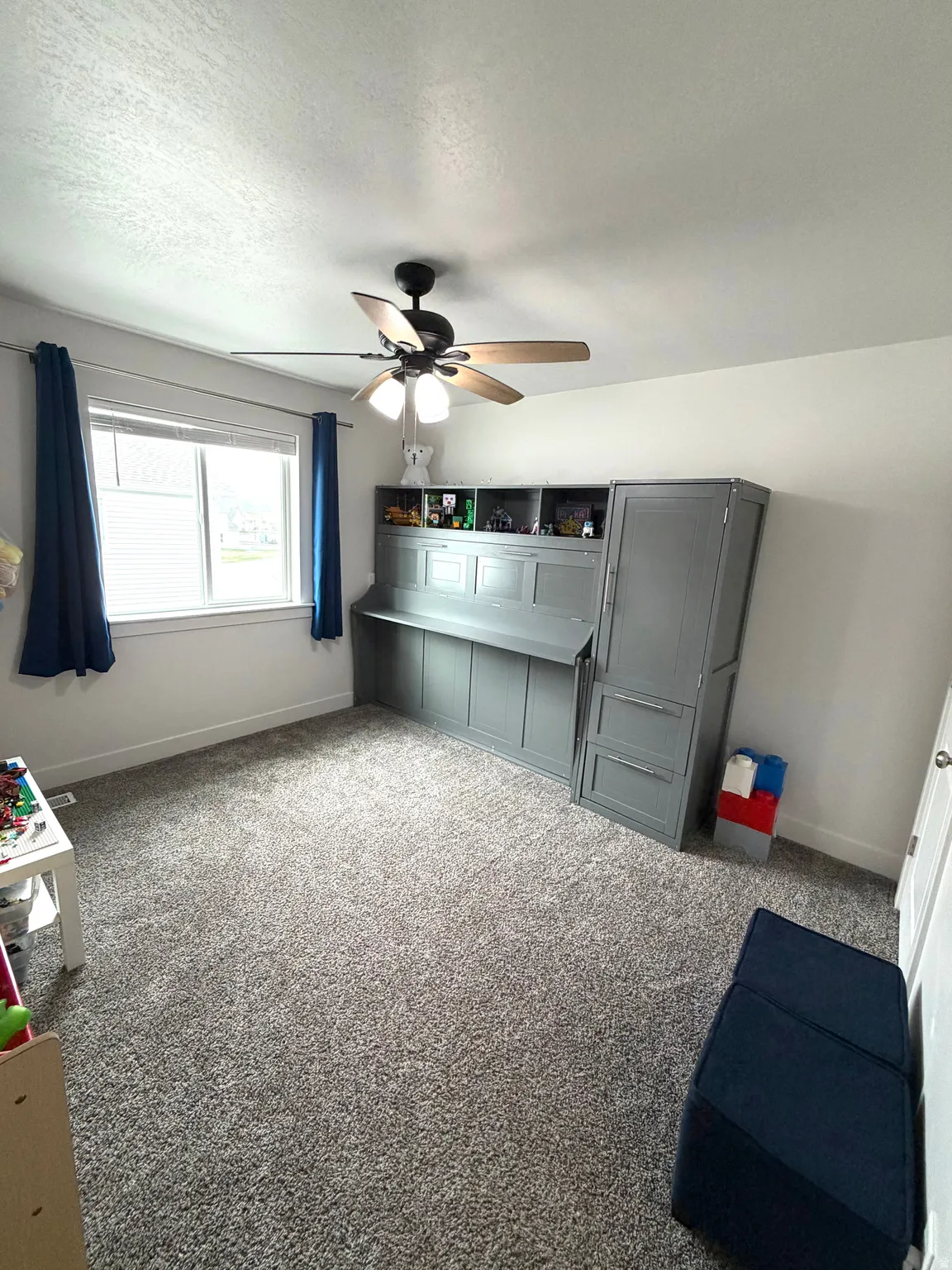 Unfurnished bedroom featuring dark colored carpet, a ceiling fan, and a textured ceiling