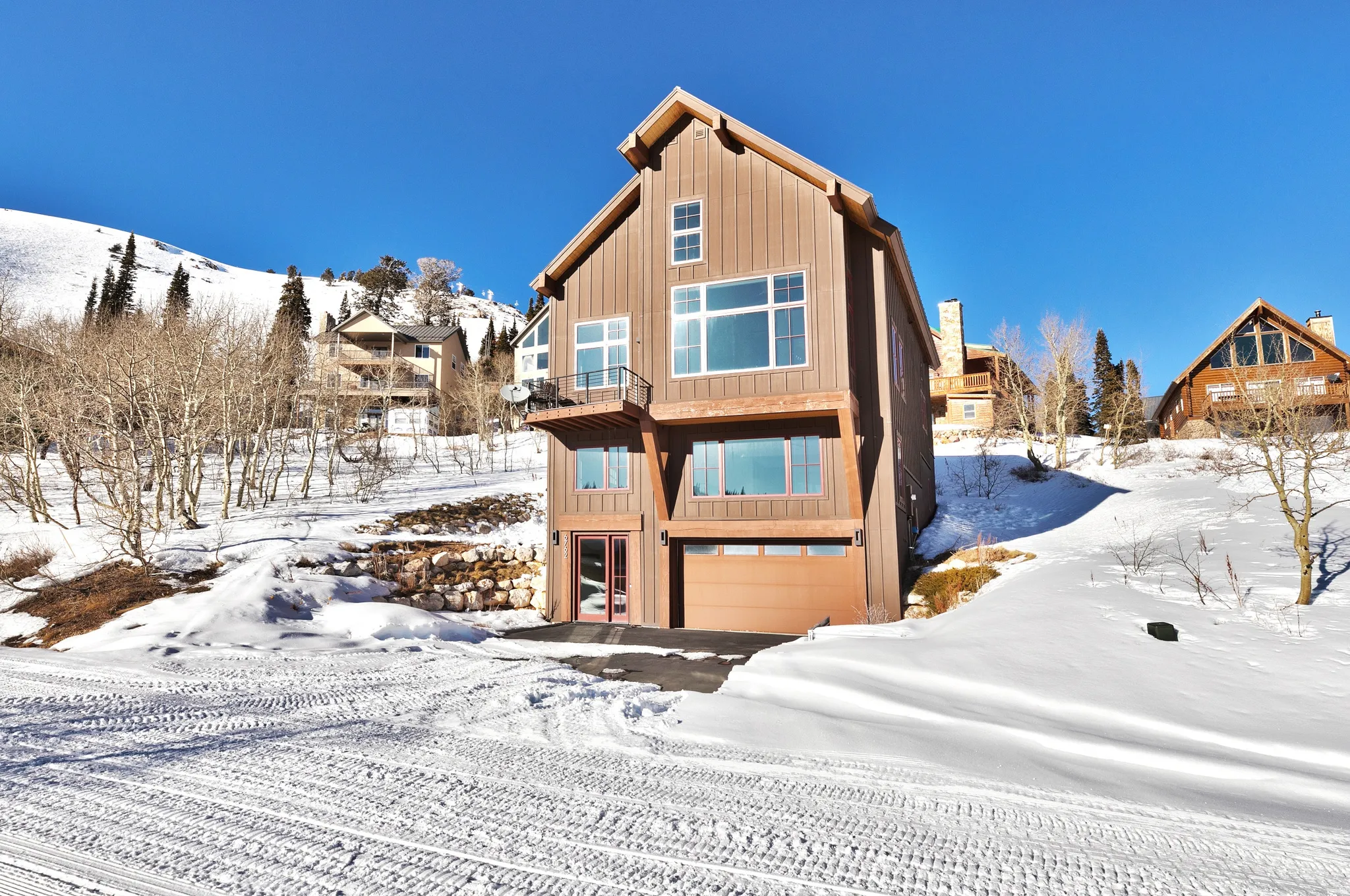 Snow covered rear of property with an attached garage and a balcony
