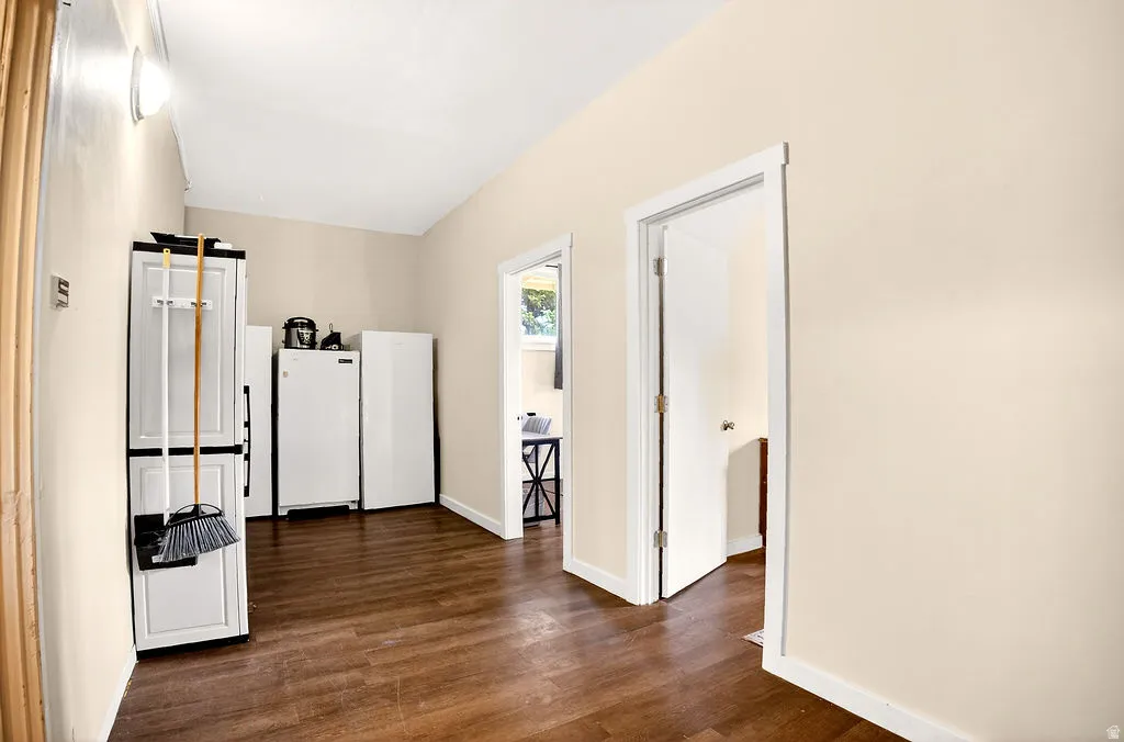 Hall with dark wood-type flooring and baseboards