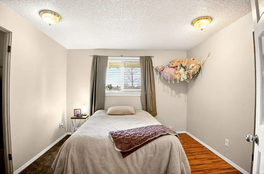 Bedroom with a textured ceiling and dark wood finished floors