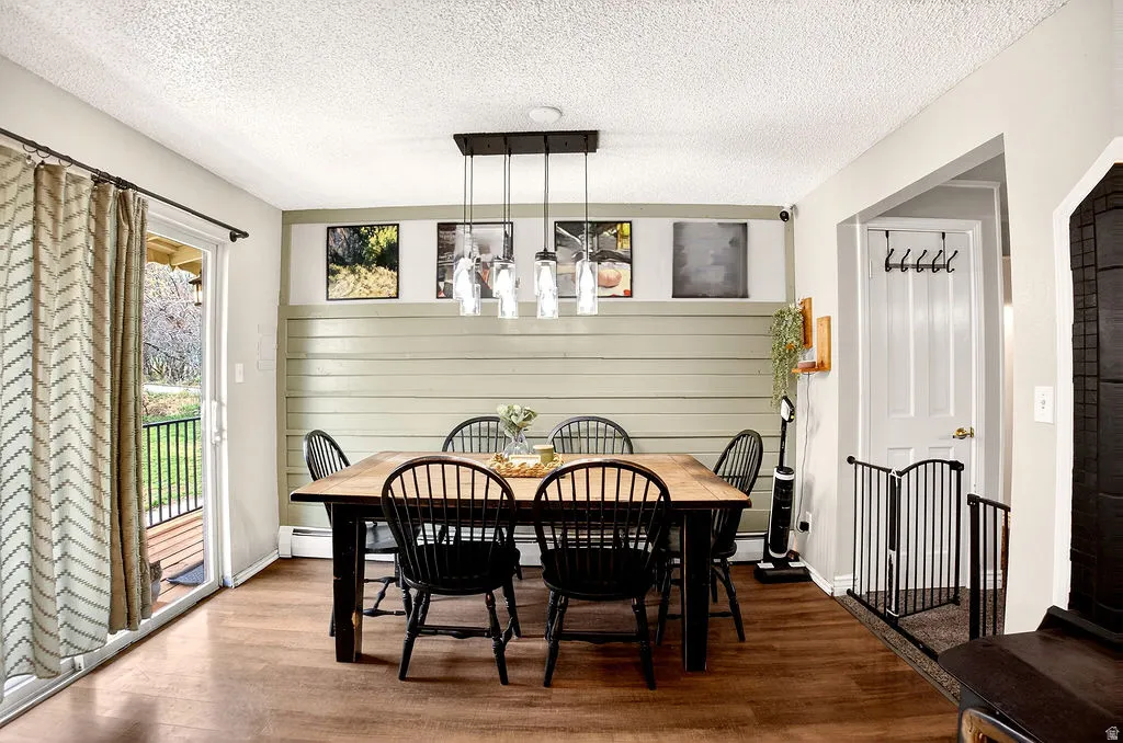 Dining space with wood finished floors, a textured ceiling, and a baseboard heating unit