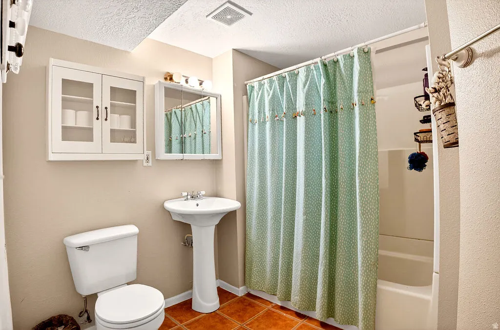 Full bathroom featuring a textured ceiling, tile patterned flooring, and shower / tub combo with curtain