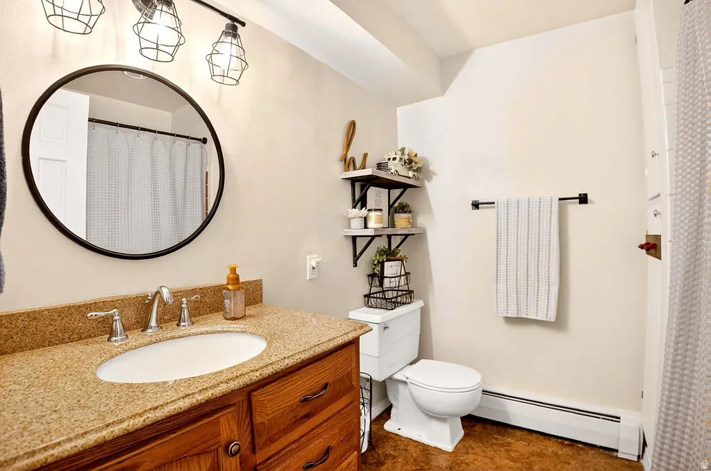 Full bathroom featuring a baseboard heating unit, vanity, and curtained shower