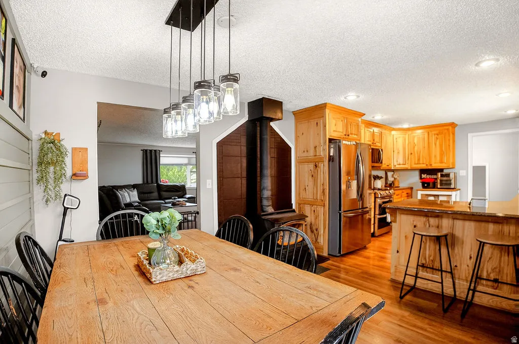 Dining room with a wood stove, a textured ceiling, light wood-style flooring, and recessed lighting